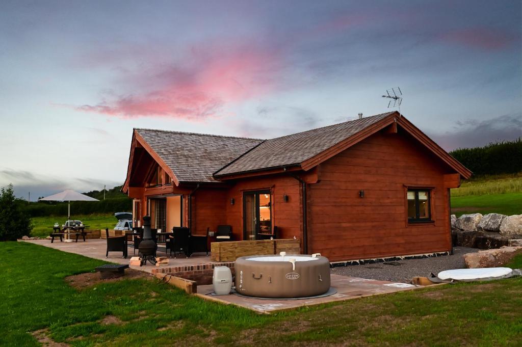 a log cabin with a hot tub in front of it at Cuddfan Lodge on a Gorgeous Private Lake in Newport
