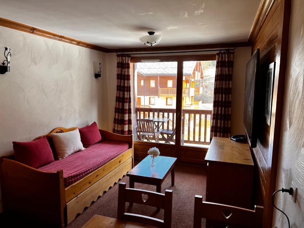 d'un salon avec un canapé et un balcon. dans l'établissement Les Alpages location appartement 202, à Lanslebourg-Mont-Cenis