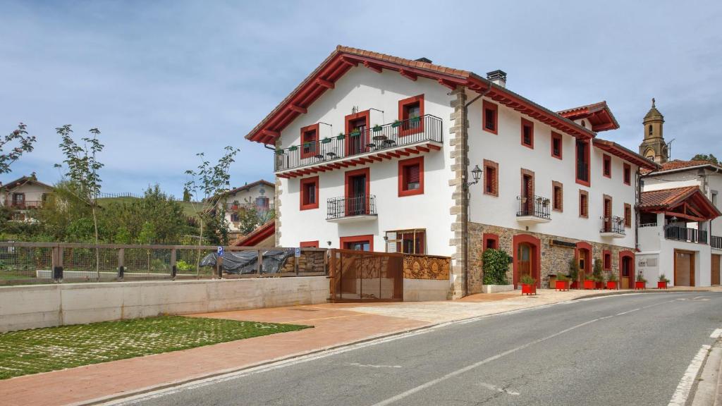 un edificio blanco al lado de una calle en Apartamentos turísticos Rurales ITURBURUARENA, en Alcoz