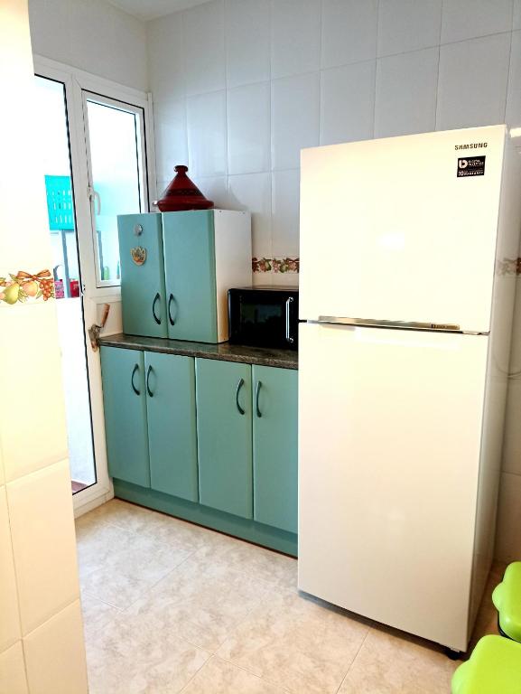 kuchnia z niebieskimi szafkami i białą lodówką w obiekcie Apartamento en zona Atalaya con garaje y WIFI w mieście Conil de la Frontera