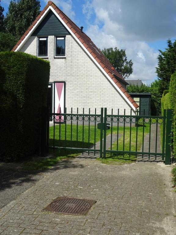una cerca frente a una casa blanca en Kustverhuur, Park Schoneveld, Zeemeeuw 164, en Breskens
