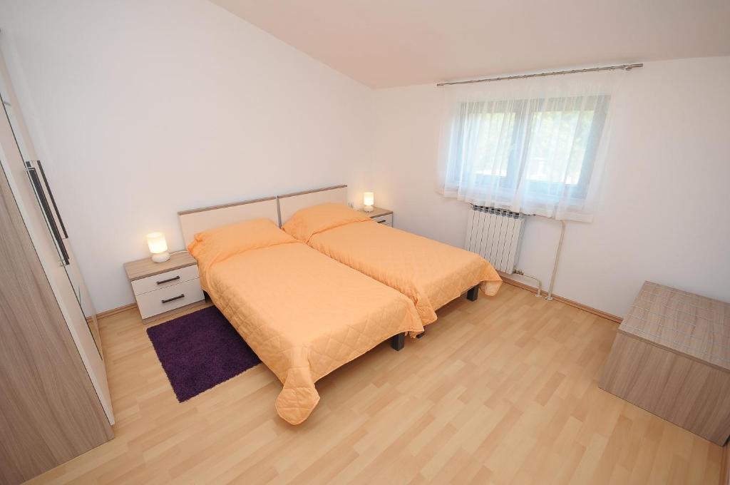 sypialnia z łóżkiem z pomarańczową pościelą i oknem w obiekcie Apartament VV w Puli