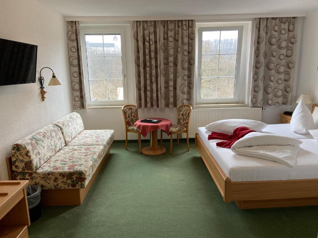 um quarto de hotel com duas camas e um sofá em Das Muldenschlösschen - Gästehaus & Restaurant em Lunzenau