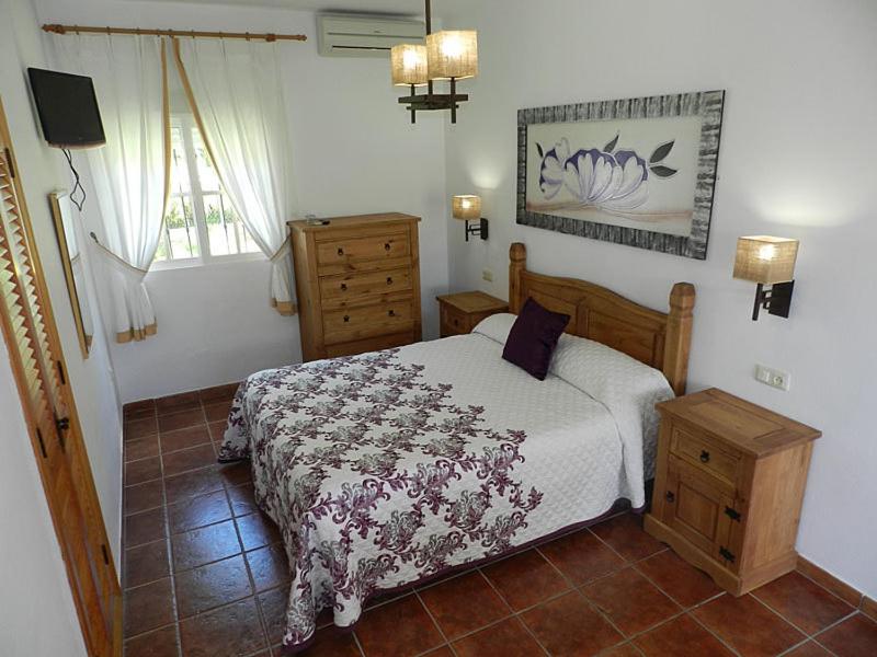 a bedroom with a bed and a dresser and a window at Hostal Las Acacias in Los Caños de Meca