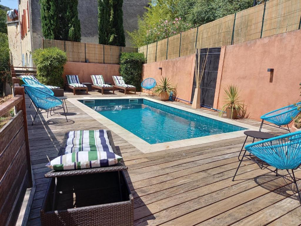 una piscina en una terraza de madera con sillas y mesa en Hôtel Restaurant Notre Dame, en Collobrières