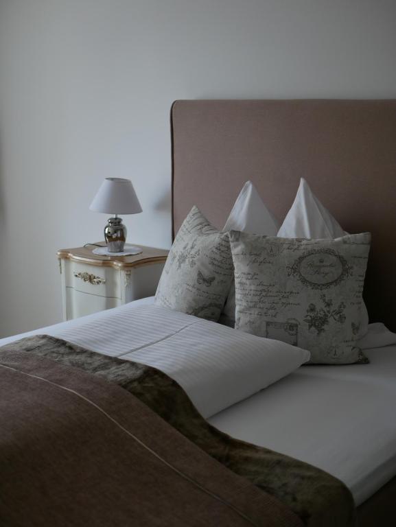 a bed with white sheets and pillows next to a lamp at Gasthof Ginzinger in Mauerkirchen