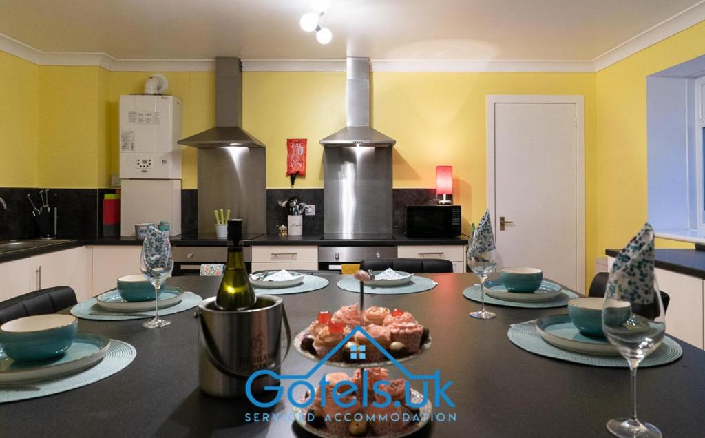 亨特利的住宿－Dunedin House -Contractors - Business Travellers，厨房配有带盘子和酒杯的桌子