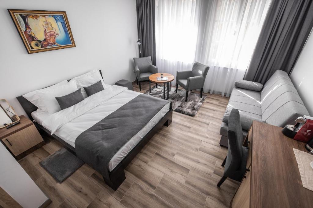 a bedroom with a bed and a couch and a table at Vila Greta by Hotel Ramonda in Rtanj