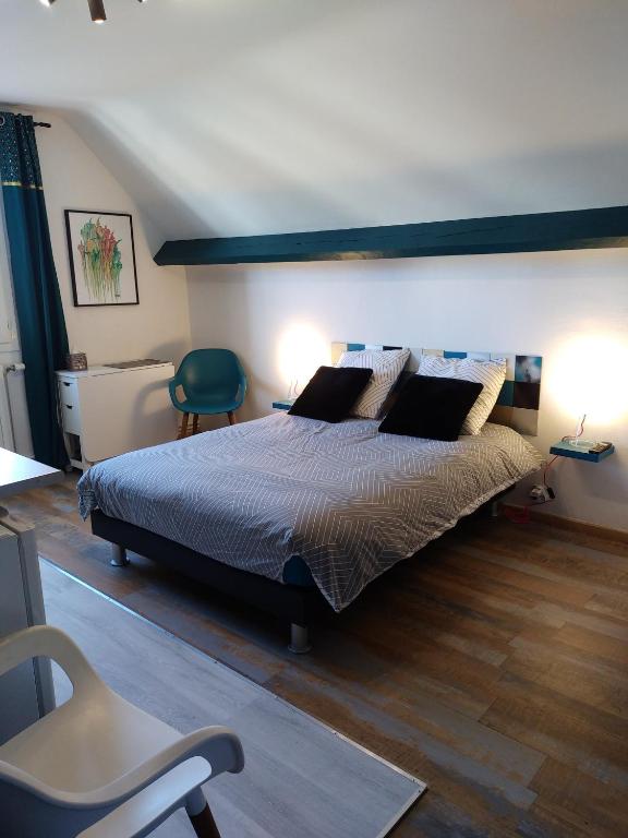 - une chambre avec un grand lit et une chaise verte dans l'établissement Studio et chambres d'hôtes les nuits de Gesnes, à Saint-Germain-du-Corbéis