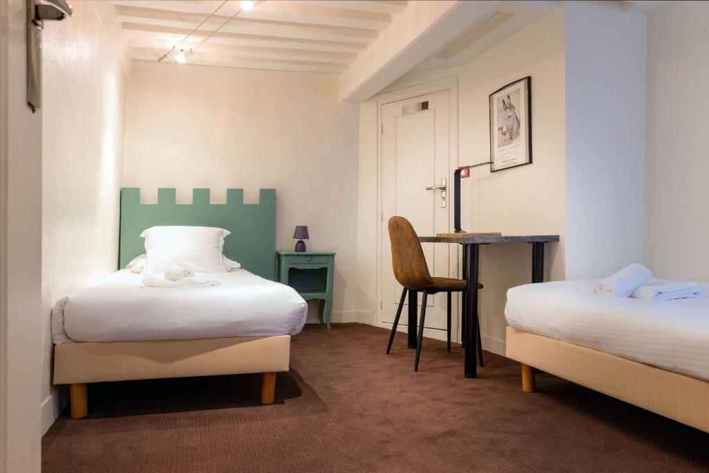 a bedroom with two beds and a desk with a chair at Hotel Le Dauphin in Honfleur