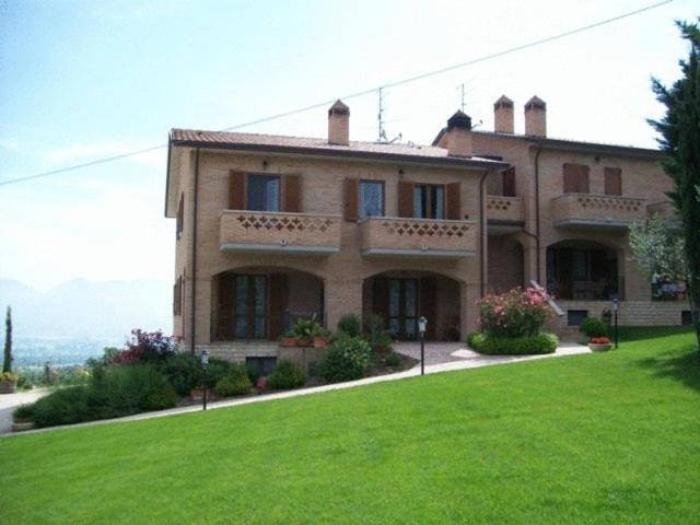 una casa grande con un césped verde delante de ella en La Collina Del Sagrantino en Montefalco