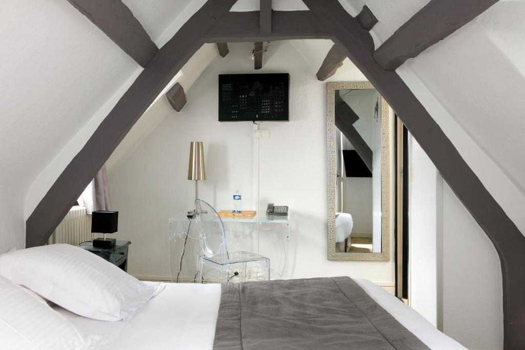 a bedroom with a white bed and a mirror at Hotel Le Dauphin in Honfleur