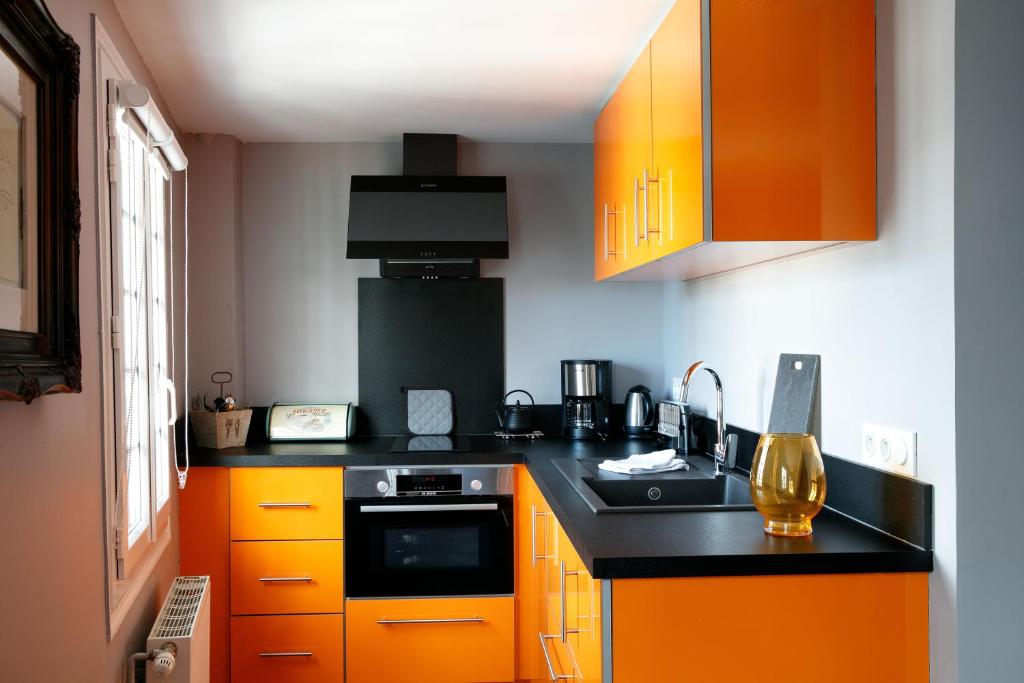 a kitchen with orange cabinets and a black counter top at Hotel Le Dauphin in Honfleur