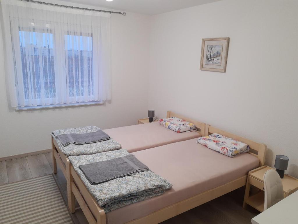 two twin beds in a room with a window at Apartman Valentic in Vinkovci