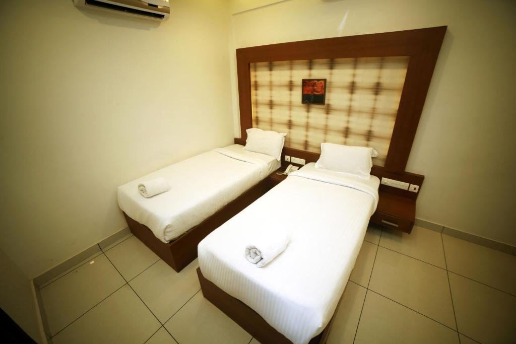 two beds in a small room with white sheets at AURA RESIDENCY in Payyannūr
