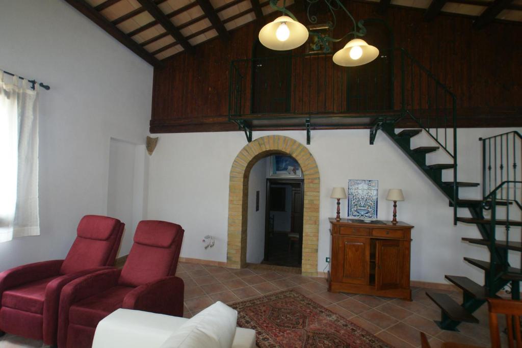 a living room with red chairs and a staircase at Cottage Bruca in Brucanuova