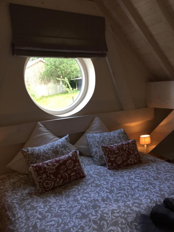 Bett mit Kissen in einem Zimmer mit Fenster in der Unterkunft Le Clos de Jabanelle in Ciney