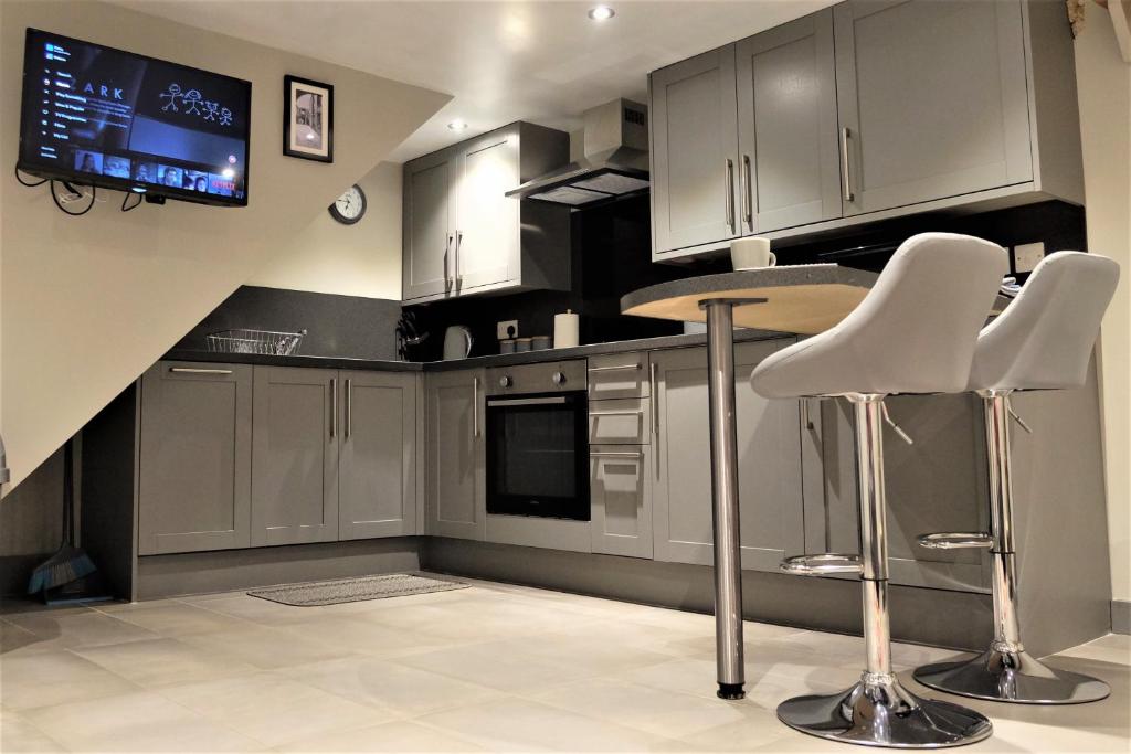 a kitchen with gray cabinets and white chairs and a tv at 18th Century courtyard property in Settle