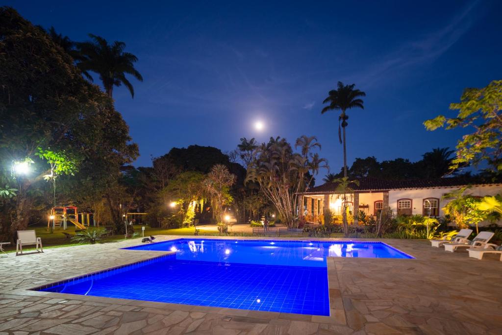 a swimming pool in front of a house at night at Pousada Chácara Das Acácias in Paraty