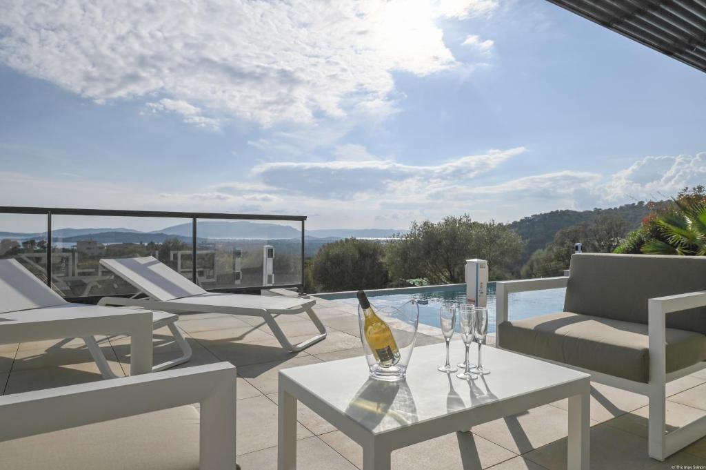- une terrasse avec une table et des chaises ainsi qu'une bouteille de vin dans l'établissement Villa neuve et luxueuse vue mer proche Portovecchio, à Zonza