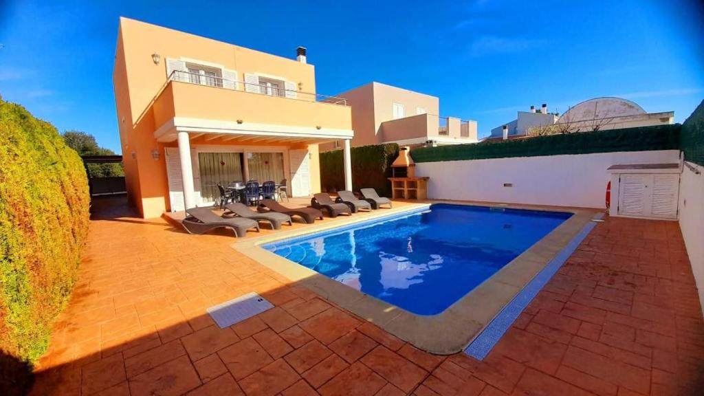 a house with a swimming pool in front of a house at Villa Lorena in Sa Caleta
