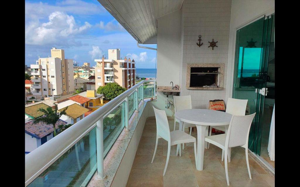 balcón con mesa, sillas y vistas a la ciudad en Apartamento Cobertura PALMAS DO ARVOREDO para 7 pessoas a 250m do mar com terraço e vista maravilhosa, en Governador Celso Ramos
