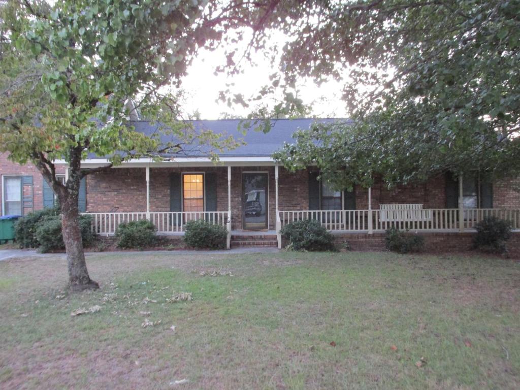 ein Backsteinhaus mit einer Veranda und einem Baum in der Unterkunft Cayce Charm Minutes to Downtown Columbia in Cayce