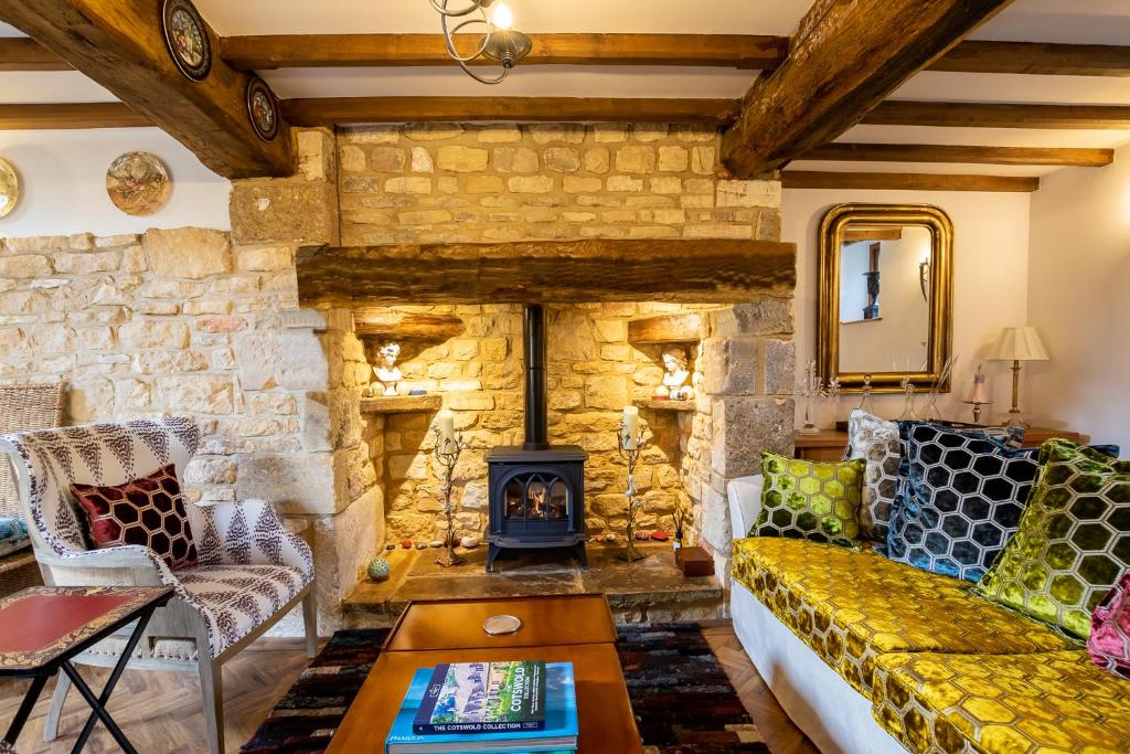 a living room with a couch and a stone fireplace at Granary Cottage - Luxury Barn Conversion in Weston Subedge