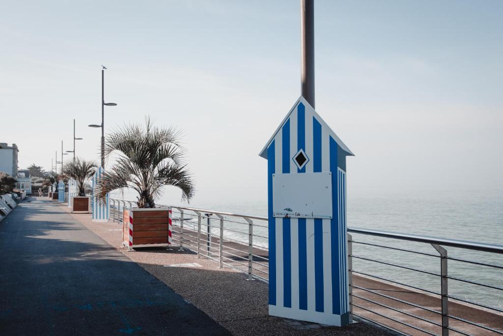 un panneau bleu et blanc sur le côté d'une plage dans l'établissement MON DADA, à Granville