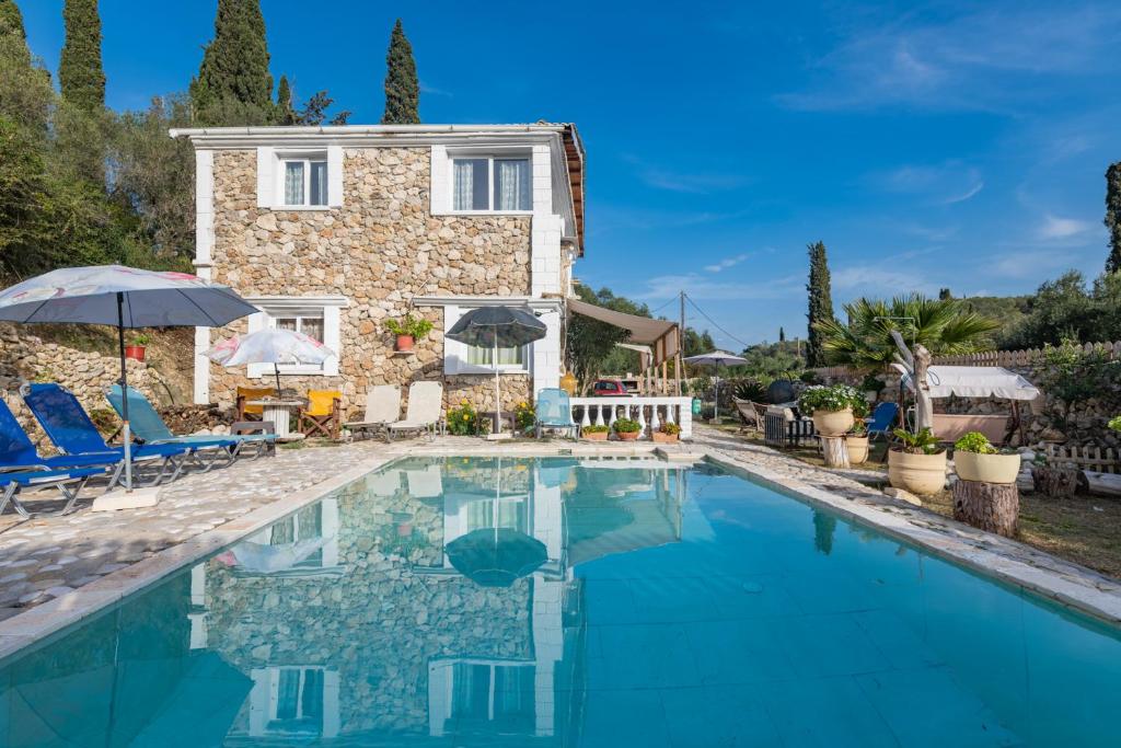 a villa with a swimming pool in front of a house at Stelios Stone House Sinarades in Kouramádes