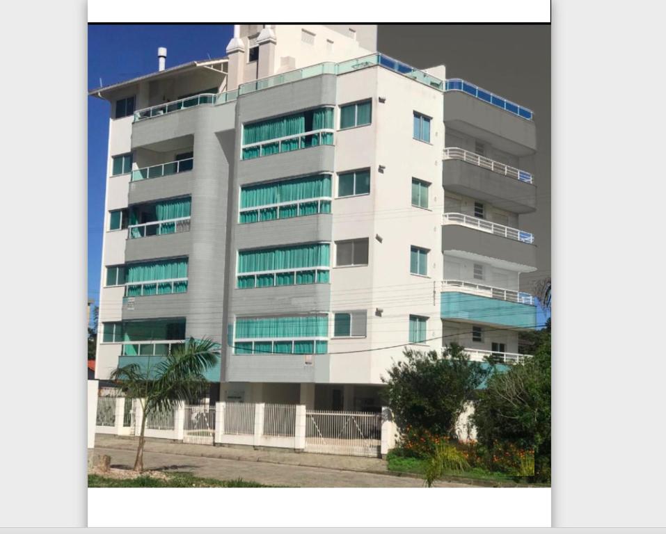a tall white building with many windows at Apartamento Cobertura PALMAS DO ARVOREDO para 7 pessoas a 250m do mar com terraço e vista maravilhosa in Governador Celso Ramos