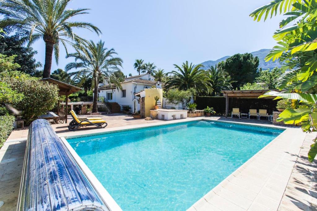 una piscina frente a una casa con palmeras en Finca Pepe 2 en Denia