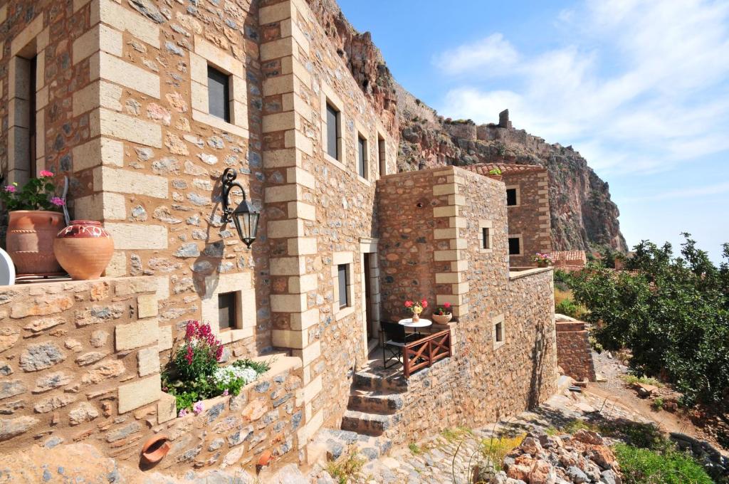 un antiguo edificio de piedra con una colina en el fondo en Izambo Guest Houses, en Monemvasia