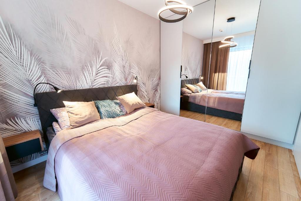 1 dormitorio con 1 cama grande y edredón rosa en LAGUNA Apartament Polanica Residence 39, en Polanica-Zdrój