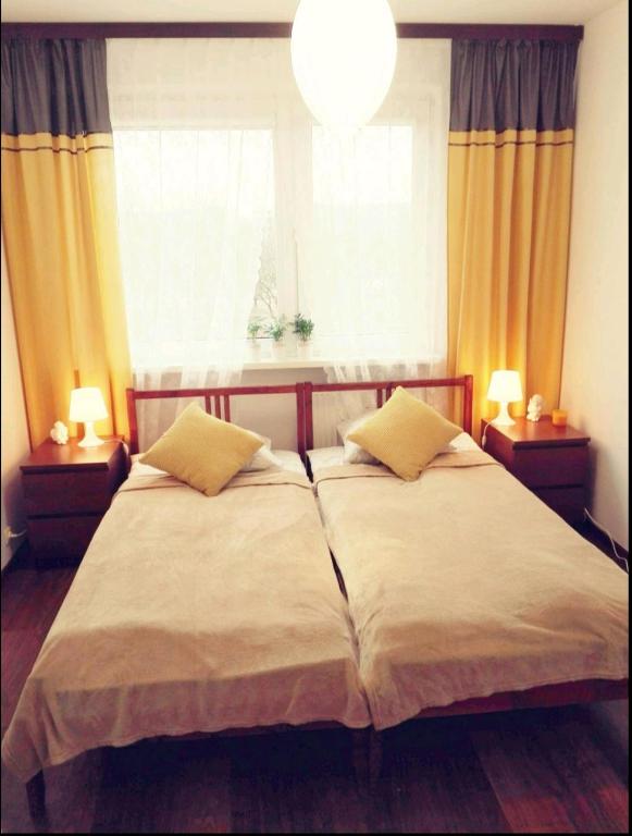 a bedroom with a bed with two pillows and a window at Zaspa Apartament in Gdańsk