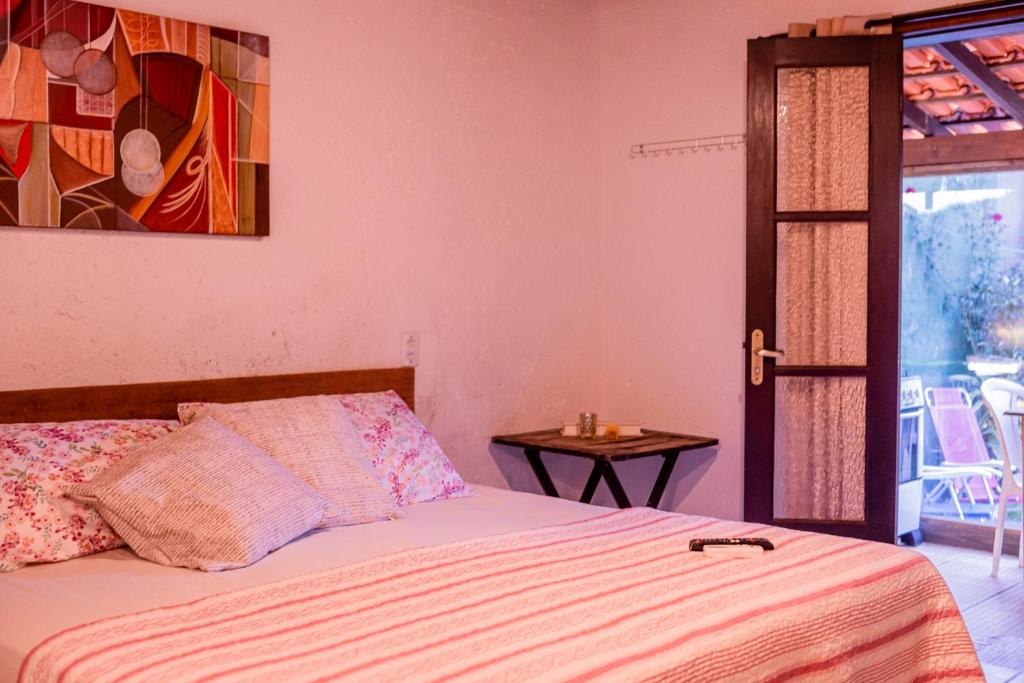 a bedroom with a bed and a table and a painting at Casinha Astral - Praia da Ferrugem in Garopaba