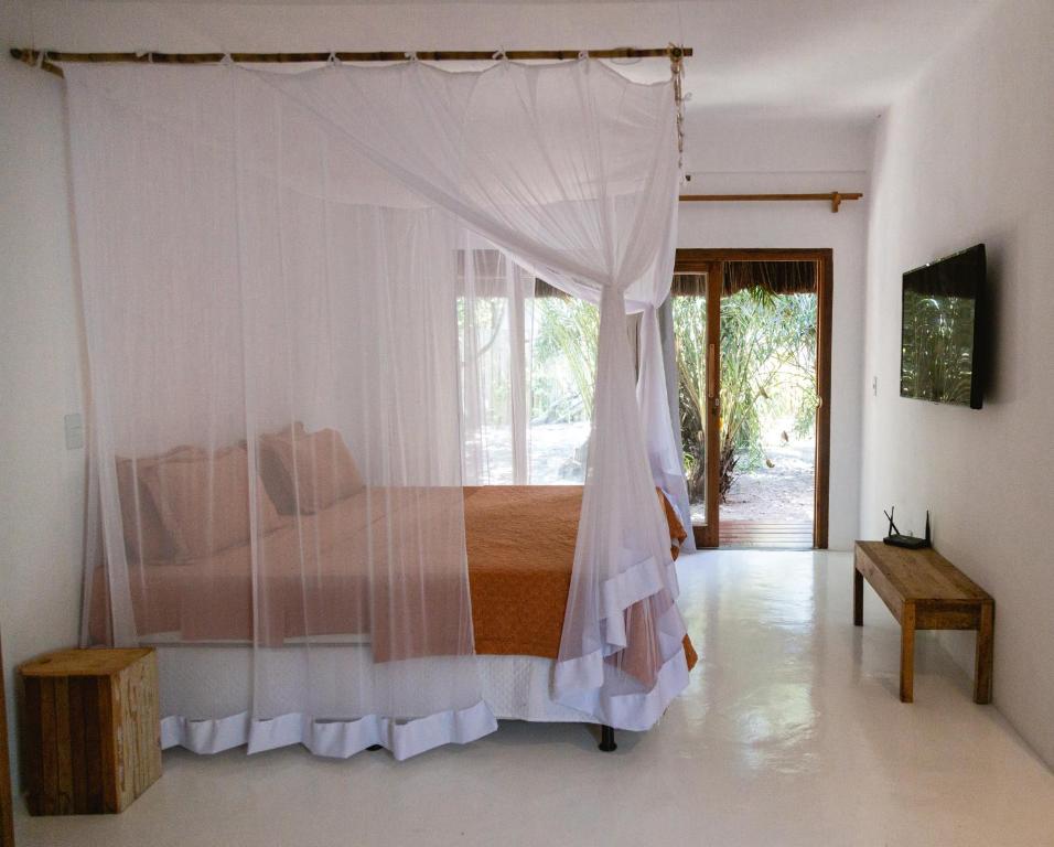 a bedroom with a bed with a mosquito net at Pousada Casa Marae in Caraíva