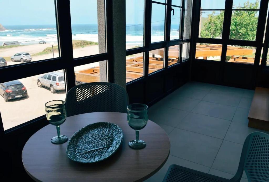 - une table avec deux verres à vin et une vue sur la plage dans l'établissement APARTAMENTOS LAS OLAS BY PANTIN, à Valdoviño