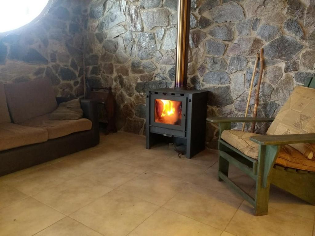 un soggiorno con stufa in una parete in pietra di Lechuzas a Córdoba