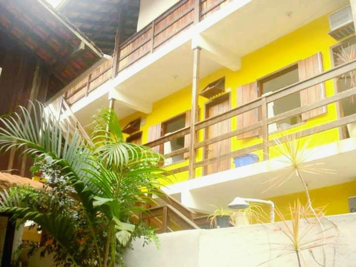 a yellow building with plants in front of it at SUITES COR DO SOL TRINDADE in Trindade