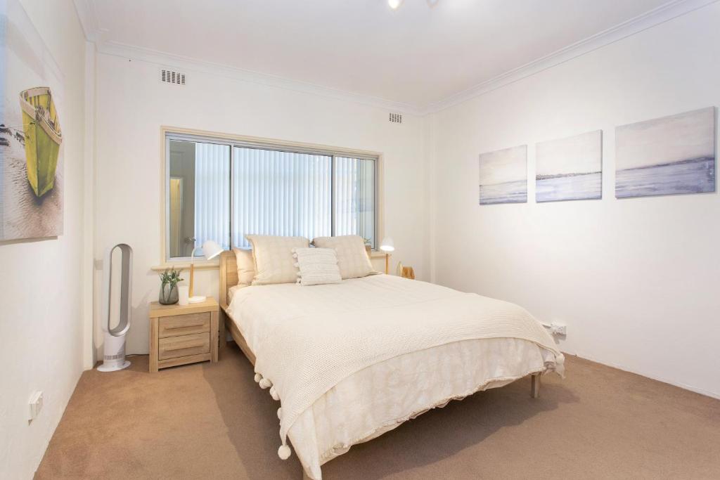 a white bedroom with a bed and a window at Arcadia Apartment - Cottesloe in Perth