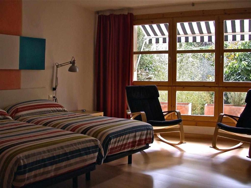 a bedroom with two beds and two chairs and a window at Hotel rural HD Riudebitlles art i allotjament in San Pedro de Riudevitlles