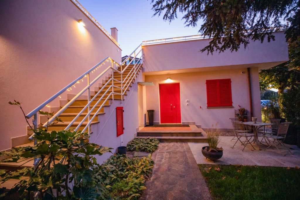 een wit huis met een rode deur en een trap bij Villa Elia Suite Room in Bellaria-Igea Marina