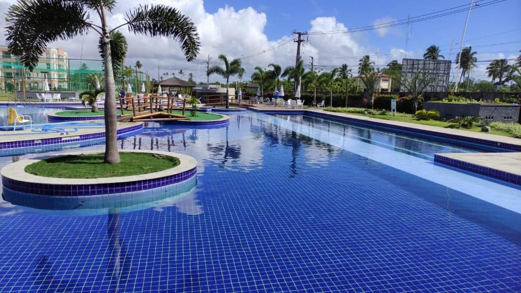 a large swimming pool with a palm tree in the middle at Muro Alto Condomínio Clube Térreo 106 in Porto De Galinhas