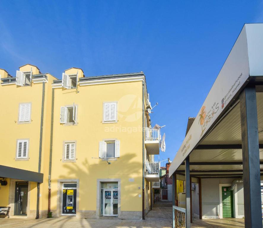 a yellow building in front of a store at Apartment Emil in Biograd na Moru