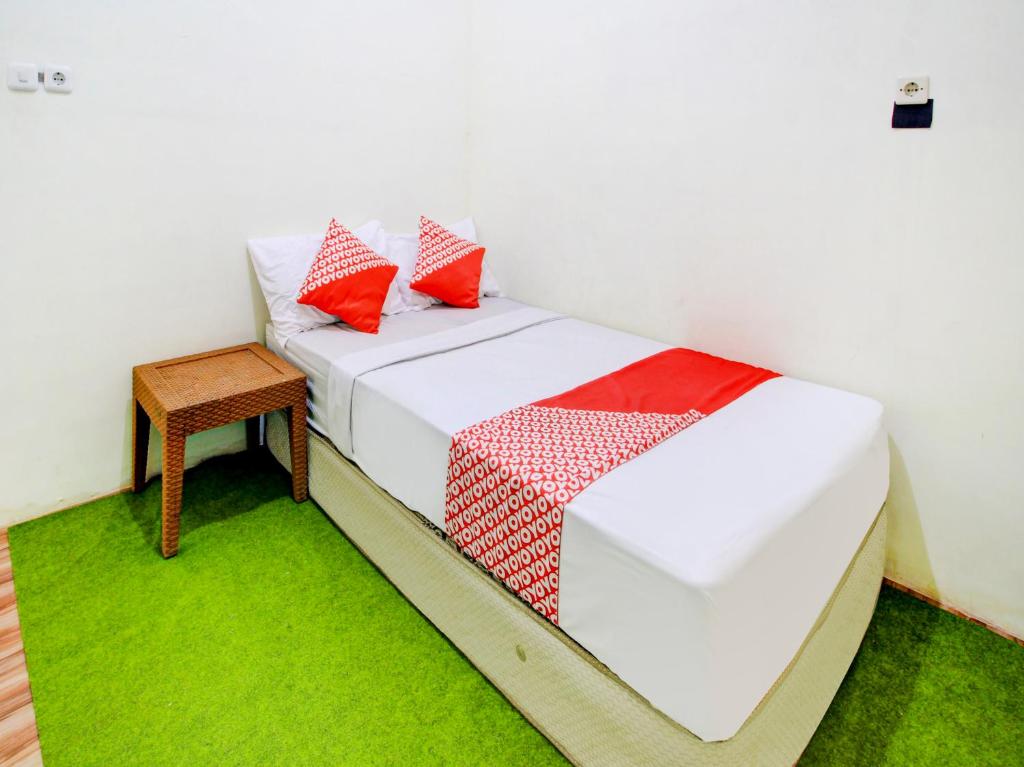 een wit bed met rode kussens en een tafel bij OYO 90725 Zeevanna Guest House Syariah in Kediri