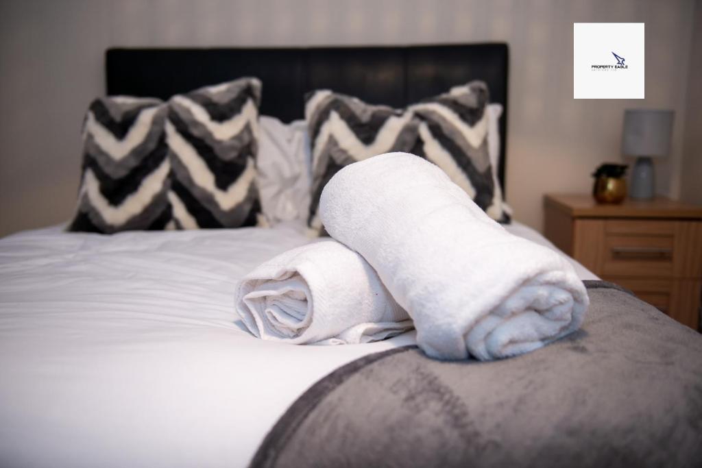 two rolled towels on a bed in a bedroom at 5Blythe House Apartments Brierley Hill in Birmingham