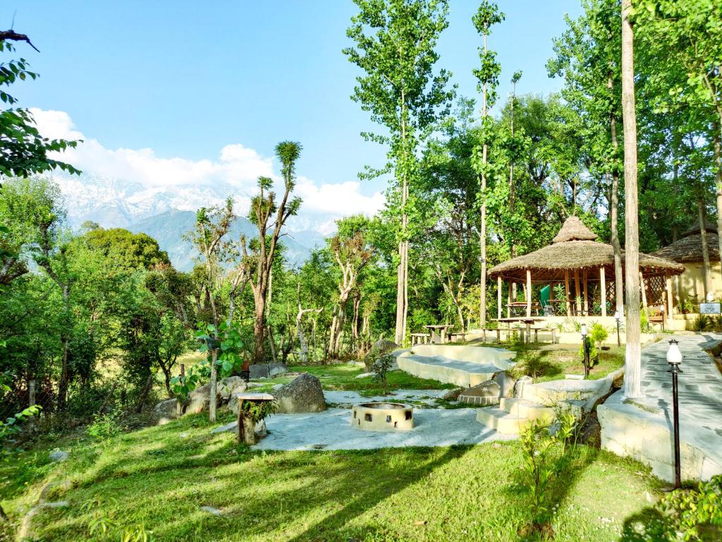 Dev Bhoomi Farms & Cottages في دارامشالا: حديقة فيها بركة و شرفة