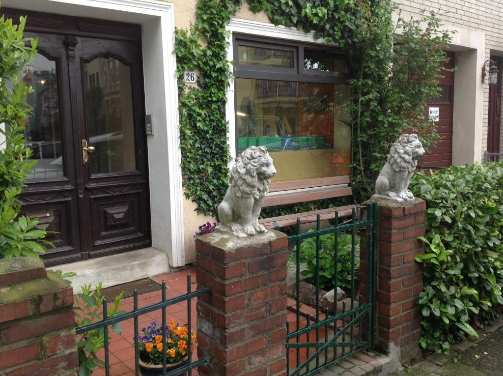 zwei Löwenstatuen auf einem Zaun vor einem Haus in der Unterkunft Gästehaus La Dolce Vita in Bremen