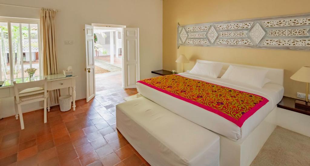 a bedroom with a large bed and a desk and a door at Nyne Hotels Rock Villa, Bentota in Bentota